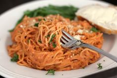 a white plate topped with spaghetti and bread