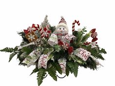 a christmas arrangement with a snowman and candy canes in the center, surrounded by greenery