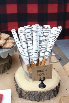 there are many cookies in the glass bowl on the wooden stand with tags attached to it