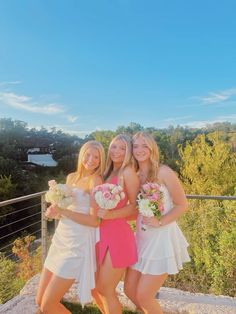 three beautiful young women standing next to each other holding bouquets in their hands and posing for the camera