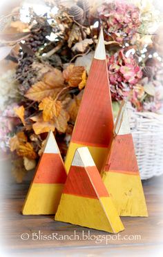 two wooden triangulars sitting on top of a table next to autumn leaves and flowers