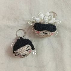 two crocheted keychains are sitting on a white cloth covered tablecloth