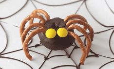 a chocolate spider with yellow eyes on it's head and webs in the background