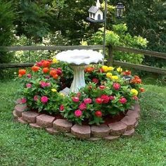 a bird bath surrounded by flowers in a garden