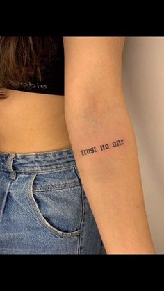 a woman with a tattoo on her arm saying trust no one