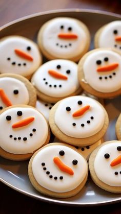 frosted cookies decorated like snowmen with carrots in the shape of faces on a plate