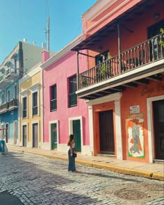 a woman standing on the street in front of colorful buildings with balconys and balconies