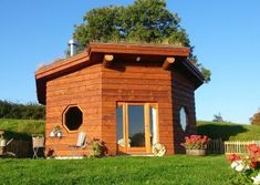 a small wooden house sitting on top of a lush green field