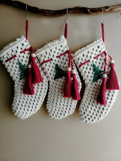 three crocheted christmas stockings hanging from a line with tassels on them