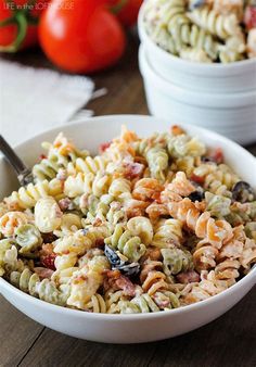 two bowls filled with pasta salad on top of a wooden table