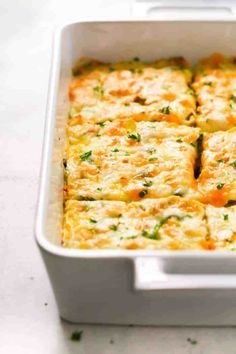 a casserole dish with cheese and vegetables in it sitting on a counter top