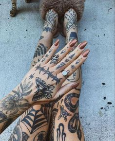 two hands with tattoos on them, one is holding the other's hand up