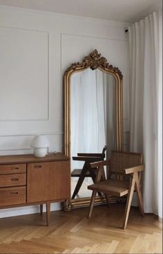 a room with a chair, mirror and table in it