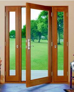 an open wooden door in a living room with a view of a green field behind it