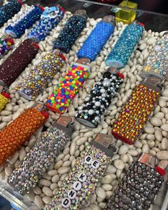 many different colored beads and bracelets are on display in a case with white rocks