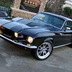 an old black mustang parked in front of a building