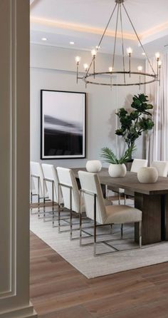 a dining room table with white chairs and a chandelier