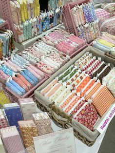 many different fabrics are on display at a market stall with price tags in the foreground