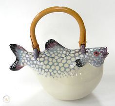 a ceramic fish shaped teapot with wooden handle