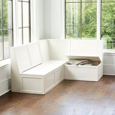 a white bench sitting in the middle of a living room next to two large windows