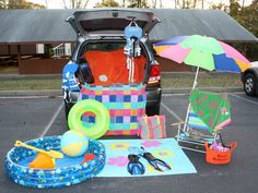 the trunk of a car is open with various items in it, including an umbrella and pool toys