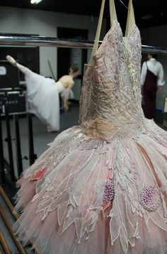 a dress is hanging on a rack in a room with other people standing around it