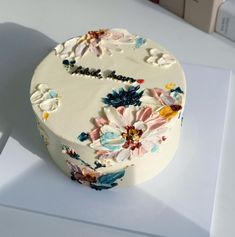 a white cake with flowers on it sitting on top of a table next to a box