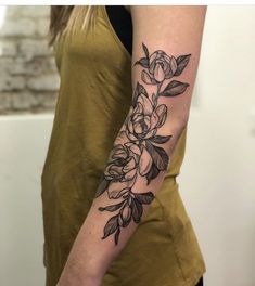 a woman's arm with flowers on it, and leaves around the armband