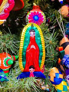 colorful ornaments are hanging from a christmas tree in the shape of a virgin mary ornament