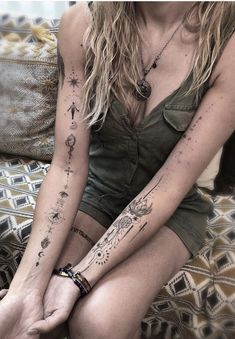 a woman sitting on top of a bed with tattoos on her arm and leg,