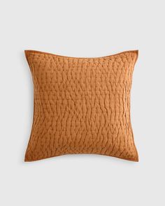 an orange pillow on a white background with a brown corded design in the middle