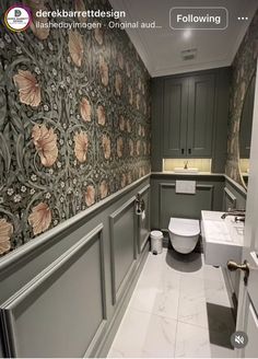 a bathroom with floral wallpaper and grey cabinets, toilet and bidet in the corner