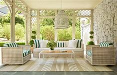 an outdoor living room with wicker furniture and green striped pillows on the couches