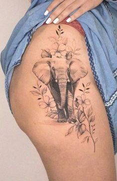 an elephant tattoo on the side of a woman's thigh, with flowers around it