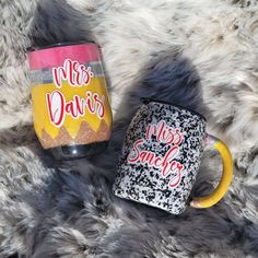 two coffee mugs sitting next to each other on a furry surface