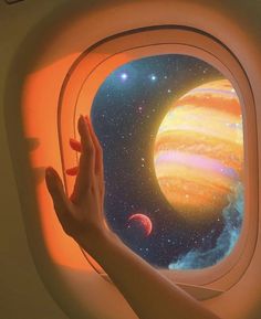 a person's hand on the window of an airplane with planets in the background