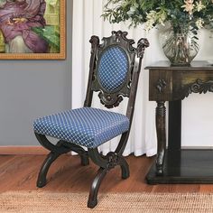 a blue chair sitting in front of a painting on the wall next to a table