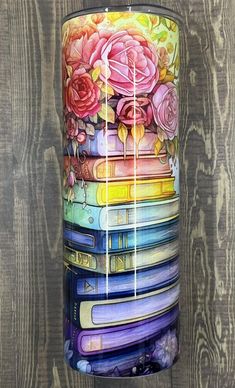 a colorful vase with flowers painted on it sitting next to a wooden wall in front of a fence