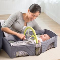 a woman playing with a baby in a playpen