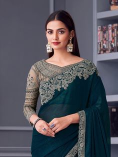 Turn heads at your next celebration with this exquisite peacock green Georgette silk saree, designed to make a statement at every party. The saree features intricate embroidered work that enhances its luxurious appeal, blending timeless elegance with modern sophistication. The lightweight yet rich texture of Georgette silk ensures comfort while exuding a regal charm, making it an ideal choice for evening parties, receptions, or festive gatherings. Its striking peacock green hue effortlessly captures attention, reflecting a bold yet graceful aura. Paired with a beige Georgette silk blouse, this ensemble creates a harmonious balance of vibrant and neutral tones, perfect for elevating your party look. The blouse is crafted to complement the saree's design, ensuring a seamless blend of comfort