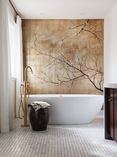 a white bath tub sitting in a bathroom next to a wall with a painting on it