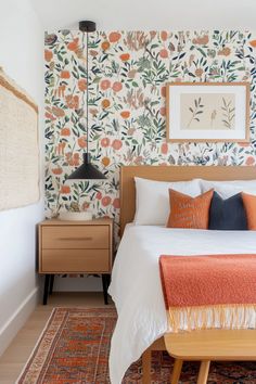 a bedroom with floral wallpaper and an orange blanket on the bed in front of it