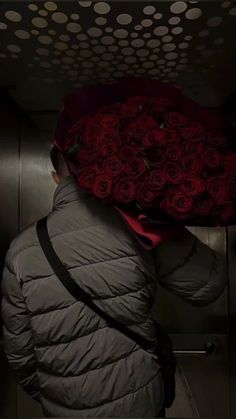 a person with a bunch of red roses on their head in an elevator area at night