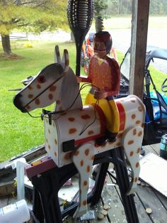 a toy horse with a man on it's back sitting on a wooden deck