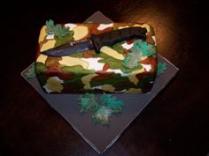 a knife on top of a camouflage cake with leaves and acrylic icing