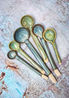 five spoons are lined up on a marble surface