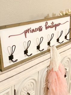 there is a sign that says princess boutique hanging on the wall next to a dress