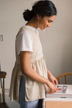 a woman standing in front of a table with a magazine on it and looking at the pages