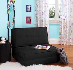 a black futon bed sitting on top of a hard wood floor next to a window