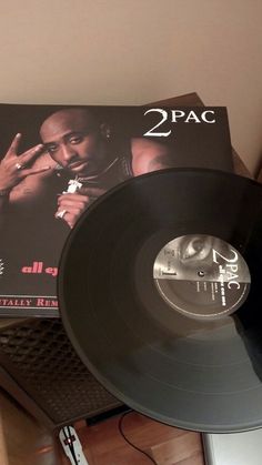 a record player is sitting on top of a table next to a box with the album 2pac